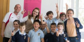 Una clase de Primaria posa con sus profesores y una de las alumnas de la Universidad de México