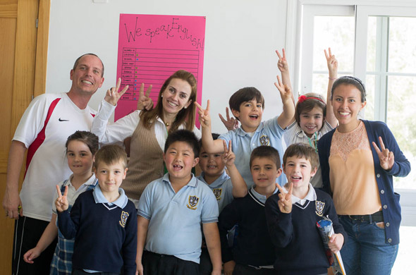 Una clase de Primaria posa con sus profesores y una de las alumnas de la Universidad de México